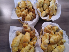 Mehrere Körbe mit frisch gebackenen Brötchen, einige mit Kräutern bestreut.