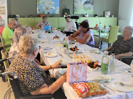 Eine Gruppe älterer Menschen feiert zusammen an einem Tisch mit Essen und Trinken.