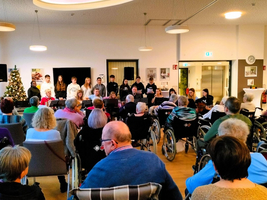 Junge Menschen führen ein Konzert vor einem Publikum in Rollstühlen auf.