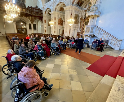 Gruppentreffen von Menschen im Rollstuhl in einer Kirche.