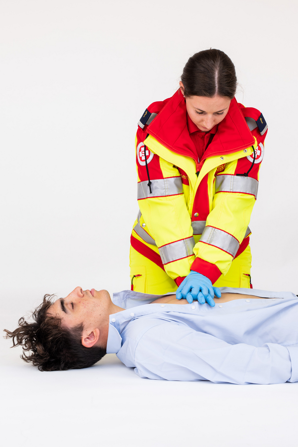 Sanitäterin zeigt Herzdruckmassage an einem Patienten