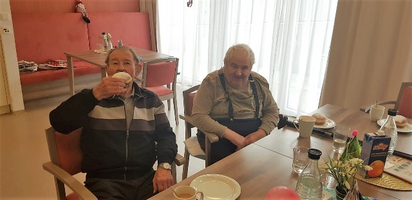 Zwei ältere Männer sitzen an einem Tisch und genießen ihr Frühstück.