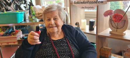 Ein Foto einer Bewohnerin in Neufeld, lächelnd in die Kamera, sieht aus wie im Friseursalon 