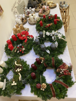Mehrere dekorative Adventskränze mit unterschiedlichen Kerzen und Weihnachtsverzierungen.