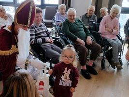 Ein kleines Mädchen überreicht Nikolaus ein Geschenk in einem Seniorenzentrum.