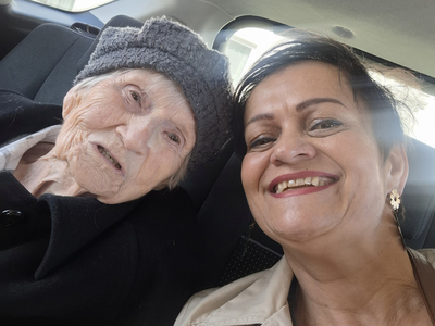 Eine Frau und eine ältere Dame lächeln glücklich in einem Auto.