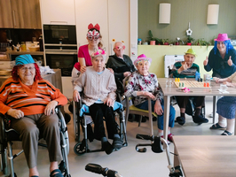 Eine fröhliche Gruppe von älteren Menschen trägt bunte Hüte und lächelt.