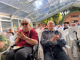 Senioren applaudieren bei einer Veranstaltung in einem Zelt.