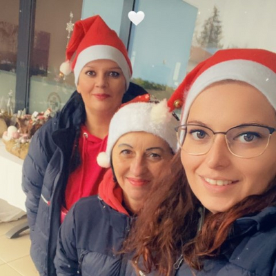 Drei Frauen tragen Weihnachtsmützen und lächeln in die Kamera.