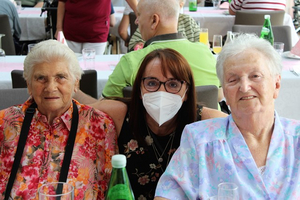 Drei Personen sitzen zusammen an einem Tisch in einem festlichen Ambiente.