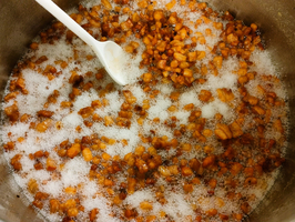 Kochen von karamellisierten Nüssen in einem Topf mit Zucker und Schaum.