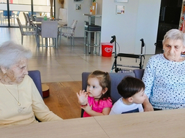 Erwachsene und Kinder sitzen an einem Tisch und interagieren miteinander.
