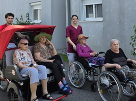 Zwei Mitarbeiter und vier Senioren vor einem Pflegeheim in Neufeld.