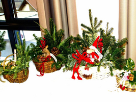 Weihnachtliche Dekoration mit Geschenkekörbchen und grünen Tannenzweigen.