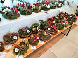 Weihnachtliche Kränze aus Moos und Naturmaterialien auf einem Tisch ausgestellt.