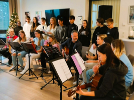 Ein Jugendchor mit Gitarre singt an einem festlich dekorierten Ort.