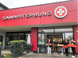 Fünf Personen stehen vor dem Gebäude des Samariterbundes mit Kisten in den Händen.