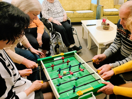 Ältere Menschen spielen gemeinsam Tischfußball in einem gemütlichen Raum.