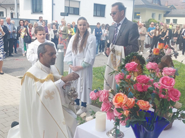 Ein Priester segnet eine Versammlung vor einer geschmückten Altarfläche im Freien.